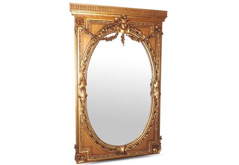 A remarkable French 18th century Régence style carved and gilt-wood grand floor mirror, The large rectangular frame with fluted top above an inset cut out frame of a trailing leafy works surrounding a very rich carved oval frame of acorn garlands, acanthus leaves and berried laurel wreath with an inset mirror plate, Crested with the smiling face of the child king Louis XV issuing swaging blossoming garlands connected to two rosettes continued with flowering pendants, The majestic mirror frame terminates to the bottom with scrolling acanthus leaves to each side